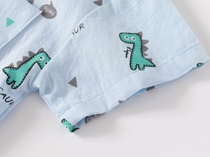Detail of light blue cotton shirt featuring cute cartoon dinosaur prints and fine stitching