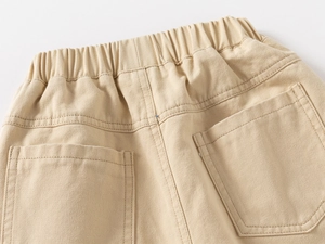 Detail view of boys beige cotton trousers showing elastic waistband and back pockets