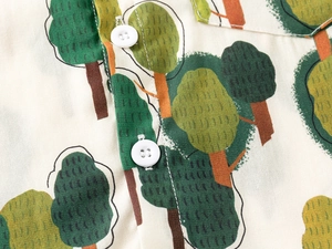 Detailed close-up of tree patterns and white buttons on a cream cotton linen shirt