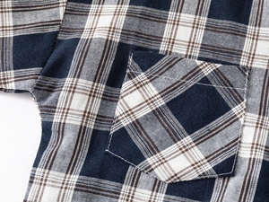 Detailed view of kids plaid shirt pocket with clean stitching and blue-brown check pattern