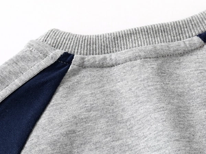Detail of grey crewneck sweatshirt featuring navy raglan sleeves and ribbed collar texture