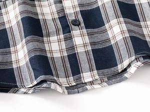 Detailed close-up of checked cotton shirt hem showing precise stitching and dark button