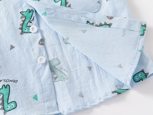 Close-up of boys light blue cotton shirt with cartoon dinosaur print and white buttons
