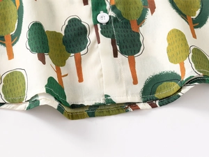 Detail view of boys cotton shirt with green tree print and white button closure