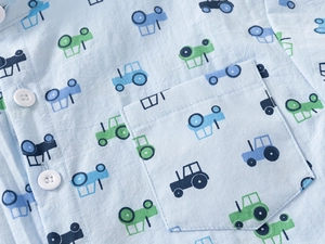 Detail of baby boy cotton shirt with cartoon tractor pattern and white button pocket
