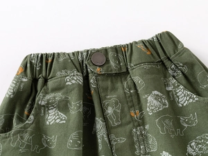 Détail de la taille élastique avec bouton en métal et motifs d'animaux sur le short vert
