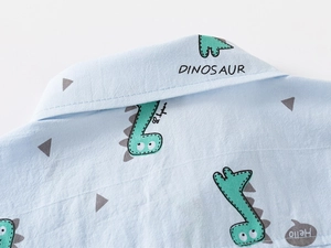 Detail of light blue cotton shirt collar with green cartoon dinosaur prints and hello text
