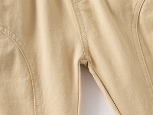 Gros plan des coutures renforcées et du tissu en coton sergé du pantalon garçon