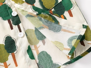 Detail view of boys' shirt featuring forest tree print and premium white button stitching