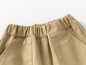 Détail du pantalon en coton kaki montrant la taille élastique et les coutures des poches