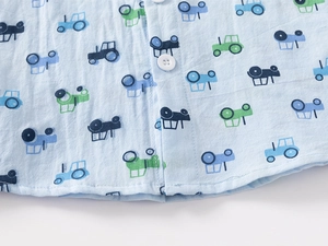 Detail of blue cotton baby shirt showing tractor prints and button-down front placket