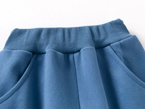 Detailed macro of kids' blue joggers featuring elastic ribbed waistband and side pockets