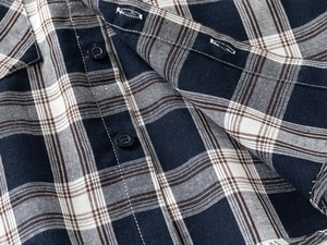Detail of navy plaid shirt featuring a four-hole resin button and premium cotton texture