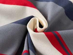 Vue macro du tissu en maille piquée à rayures pour polo de garçon en rouge, blanc et bleu