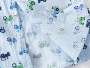 Detail of toddler shirt with tractor print, white buttons, and cotton fabric texture