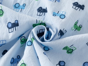 Macro shot of light blue cotton fabric with colorful cartoon tractor patterns and soft texture