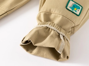 Détail du pantalon de jogging kaki avec broderie dinosaure verte et chevilles côtelées