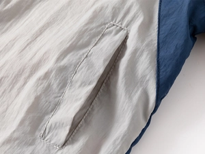 Close-up of kids hooded windbreaker showing stitching detail on side pocket and fabric