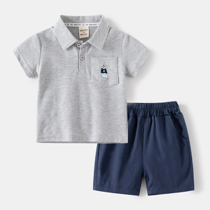 Detail eines grauen Baumwoll-Poloshirts mit Bärenstickerei und dunkelblauen Shorts
