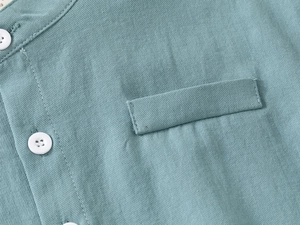 Macro view of blue-green linen shirt fabric with white buttons and breast pocket