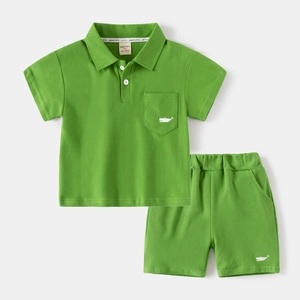 Detail of green cotton polo set for kids featuring white whale embroidery and elastic waist