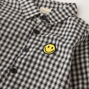 Classic black and white checkered kids shirt featuring a yellow smiley face patch
