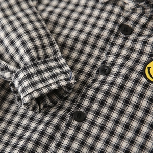 Boy's black and white plaid long sleeve shirt featuring a yellow smiley face patch