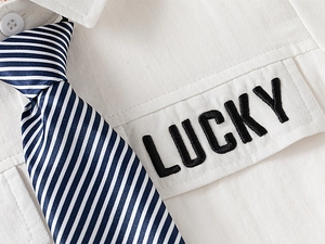 Détail d'une chemise en coton blanc avec broderie Lucky et cravate rayée incluse