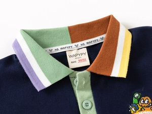 Detailed close-up of a boys cotton polo shirt featuring a colorful striped collar and monster embroidery