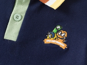 Detail of boys' polo shirt neckline with colorful striped collar and monster embroidery