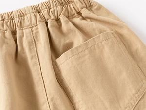 Detail of khaki cotton twill shorts showing elastic waistband and square back pocket