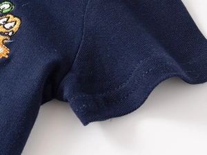 Detail of navy pique cotton polo shirt featuring colorful monster embroidery and stitching