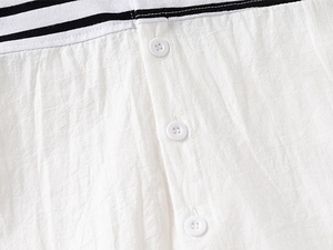 Detailed view of white cotton shirt texture with buttons and striped fabric patchwork