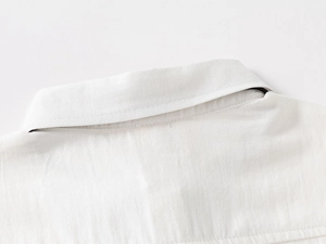 Vue détaillée du col de chemise blanc en coton avec surpiqûres fines et texture sergé
