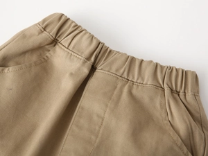 Detailed close-up of khaki cotton trousers showing elastic waistband and stitching
