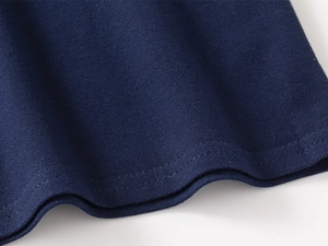 Detail of navy blue cotton polo shirt hem showing high-quality double-stitching and texture