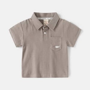 Detail of baby polo shirt collar with whale embroidery and white button on grey fabric