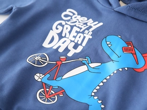 Close-up of kids navy hoodie featuring a cartoon dinosaur cycling and printed slogan