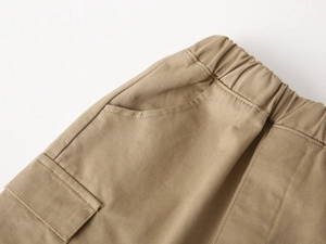 Detail of khaki cargo pants featuring elastic waistband and flap pocket on twill fabric