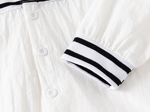 Detail of white cotton shirt cuff with black and white striped knit trim and buttons