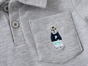 Detailaufnahme des hellgrauen Piqué-Poloshirts mit besticktem Bärenmotiv auf der Tasche