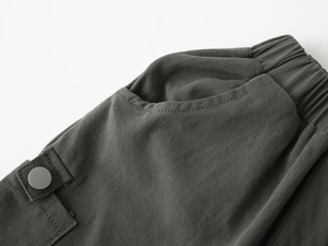Detailed view of elastic waistband and utility pocket with metal button on boy's shorts