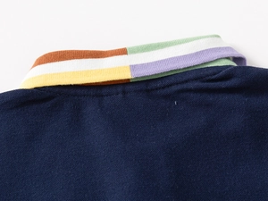 Detail of color-striped ribbed collar on a navy blue cotton piqué polo shirt for boys