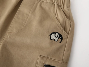 Detail of khaki kids cargo pants with elephant embroidery and metal zipper pocket