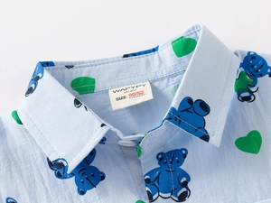 Detail of baby boy's light blue shirt collar with cartoon bear and green heart prints