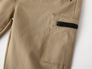 Macro detail of kids khaki cargo trousers featuring a side pocket with black zipper