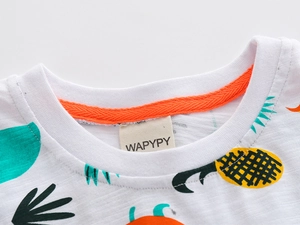 Gros plan du col de t-shirt bébé en coton flammé avec des motifs de fruits tropicaux