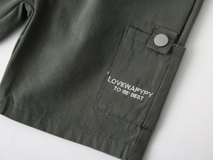 Detailed close-up of army green cargo shorts with white letter embroidery and metal snap button