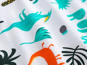 Gros plan sur le tissu en coton flammé doux avec des imprimés de dinosaures colorés