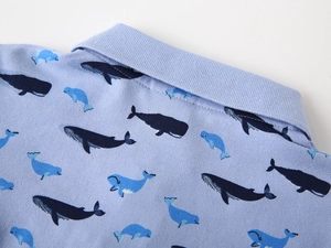 Vue détaillée du polo bleu clair avec texture tricotée et motifs de baleines mignons